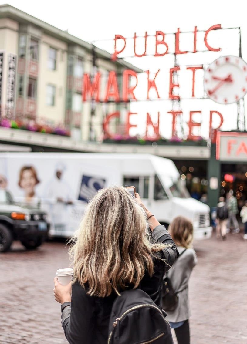 A woman capturing a photo of a sign with her smartphone.