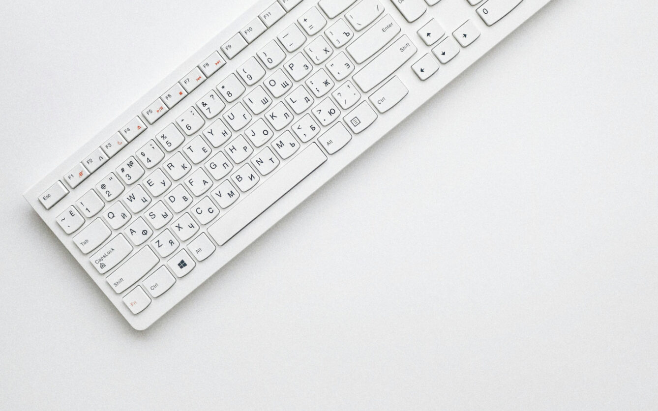 White keyboard with Russian and English letters on the keys, positioned diagonally on a plain white surface.